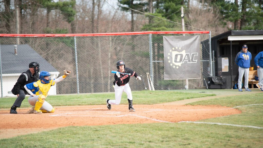 Muskingum University batter prepares to take first base after being walked by the Pitt Greensburg pitcher