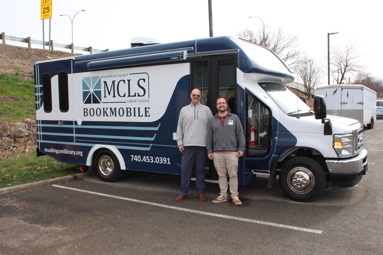 Marketing & Community Relations Director, Sean Fennell and Outreach Manager, Joshua McPeek stand with the brand new MCLS Bookmobile.