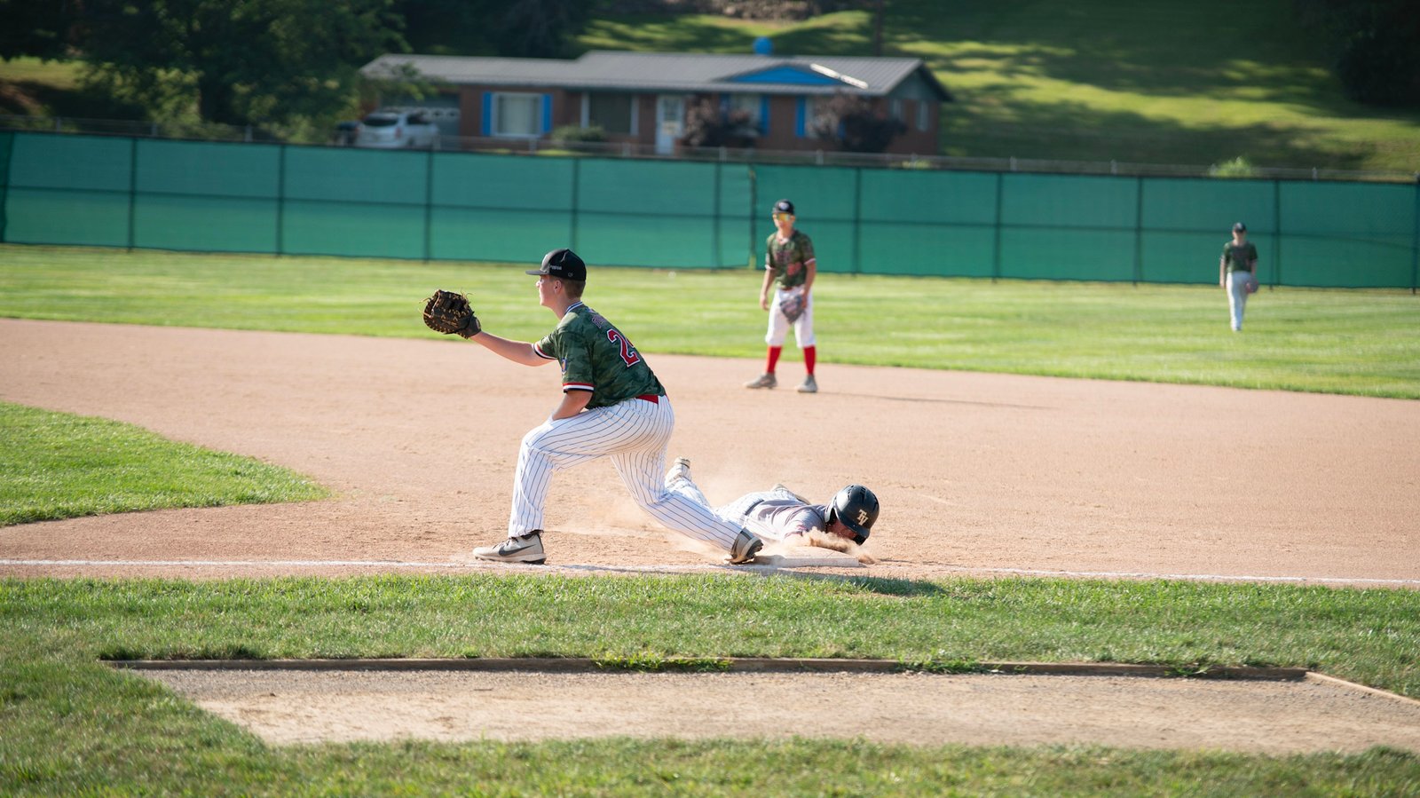 Cambridge's Greyson Forshey tries to tag a Zanesville runner trying to slide back to first base.